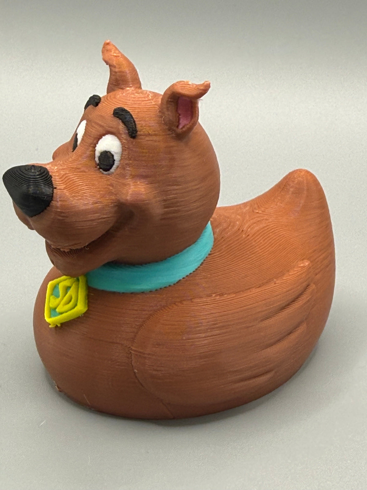 Scooby-Doo Duck – side view showing teal collar, SD tag, and brown sculpted body