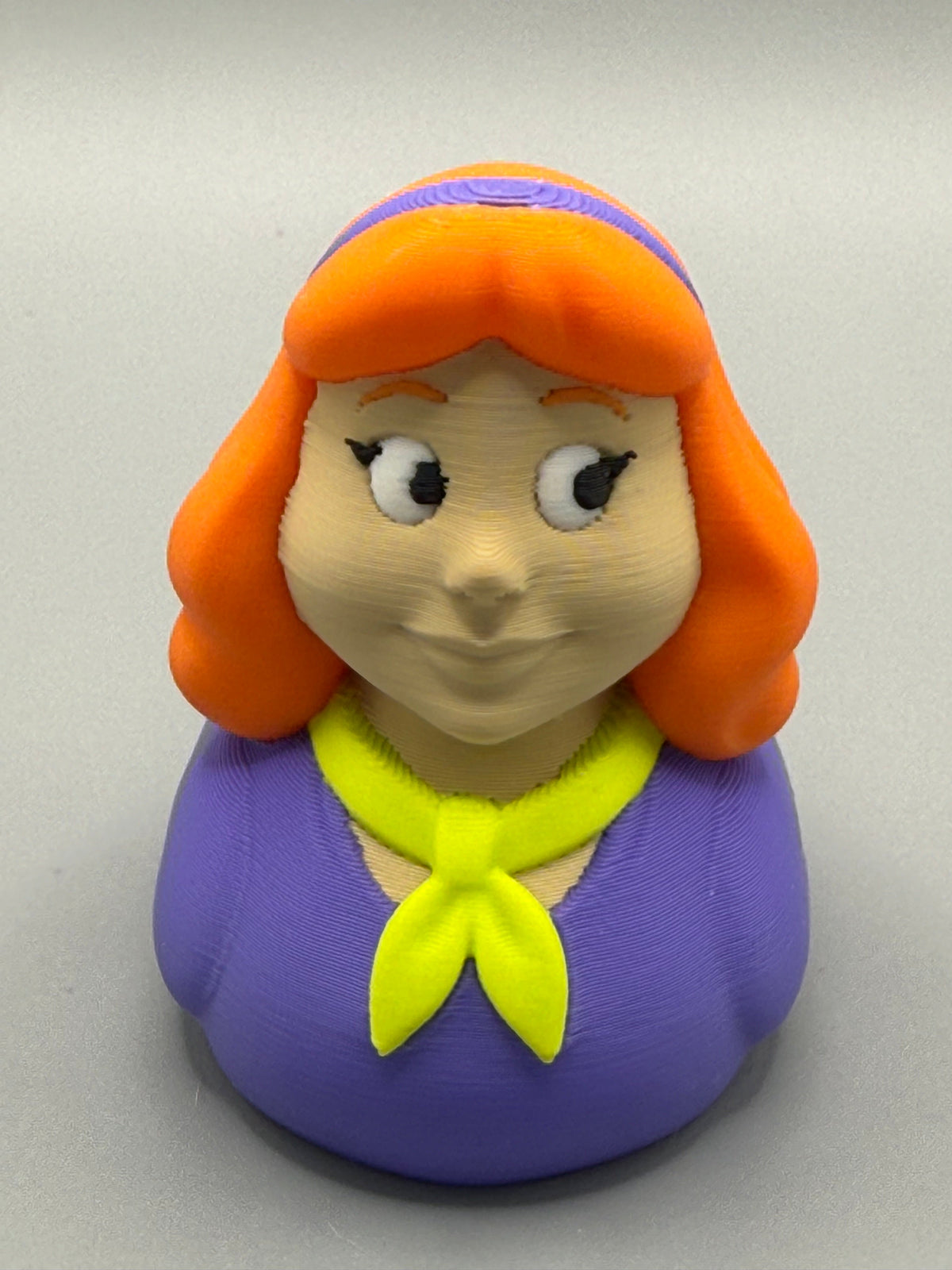 Daphne Duck – front view showing orange hair, purple headband, expressive lashed eyes and yellow neckerchief