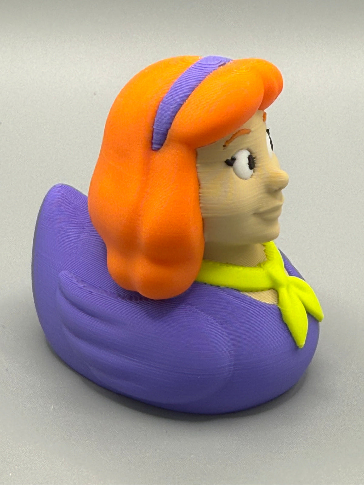 Daphne Duck – side view showing flowing orange hair, purple headband, and purple duck body with yellow neckerchief