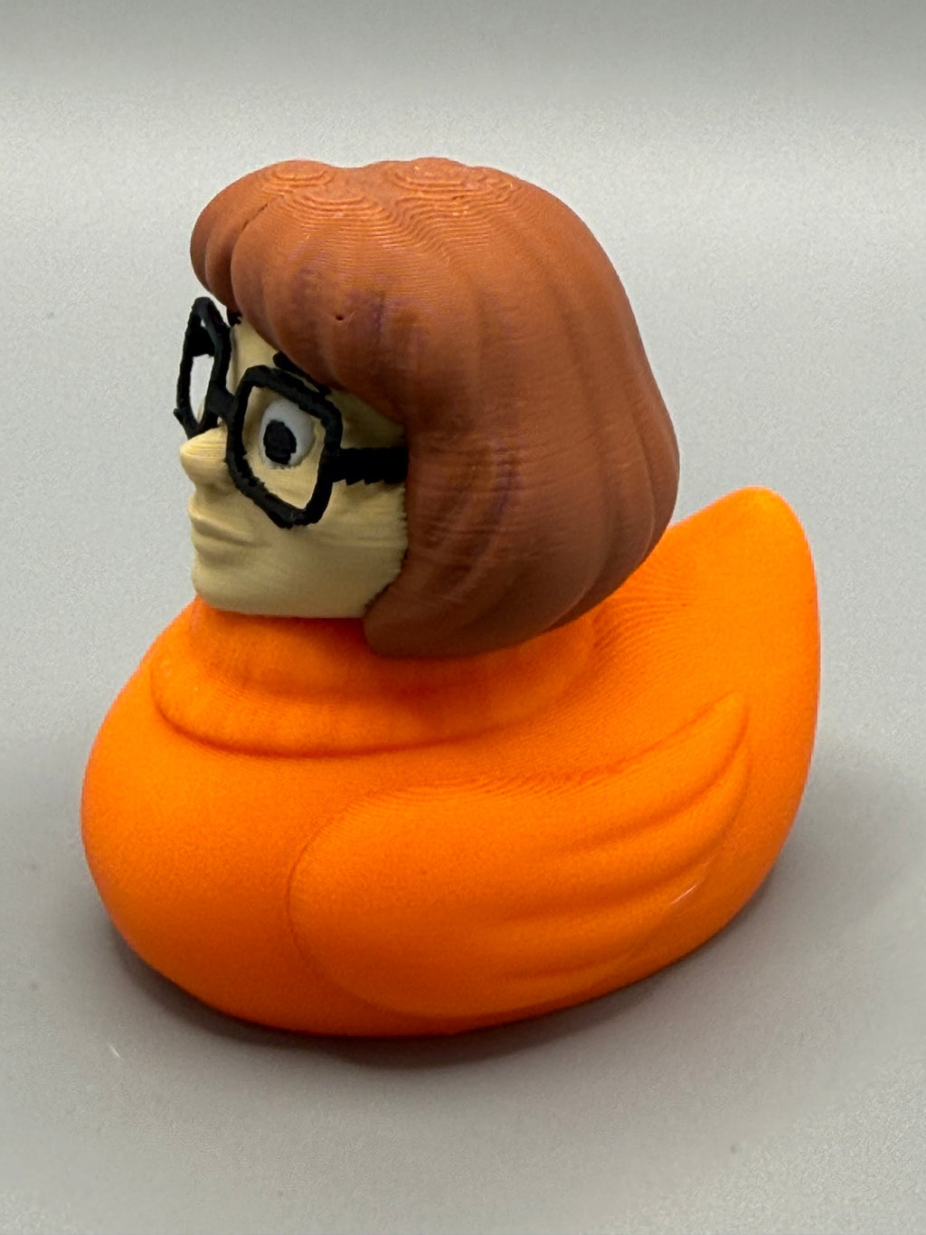 Velma Duck – side view showing reddish-brown bob, black glasses, and orange turtleneck body