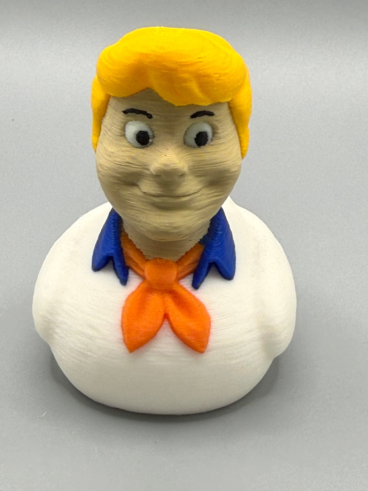 Fred Duck – front view showing chiseled face, dark brows, blue collar, and orange ascot knot